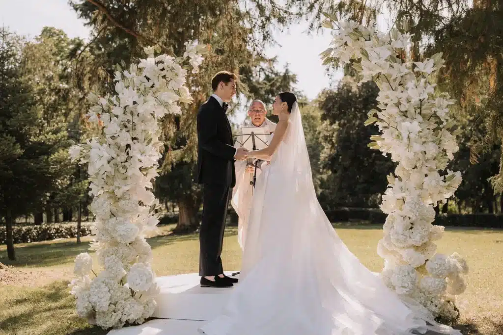 Bride and groom under floral arch at estate wedding in Italy