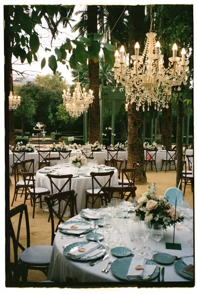Outdoor garden wedding reception with chandeliers and floral table settings